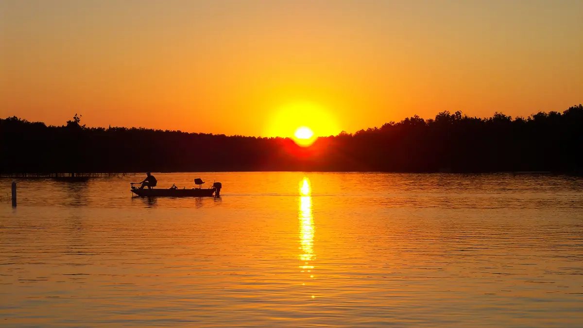 An angler in a small boat at sunset on Rough River Lake near Laurel Branch